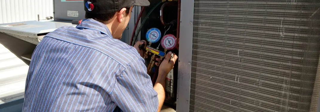 HVAC technician servicing a condenser unit in Morehead